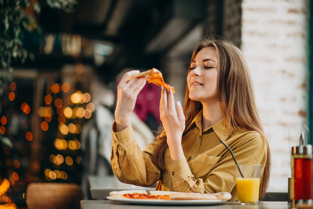 Mulher comendo um pedaço de pizza durante o verão